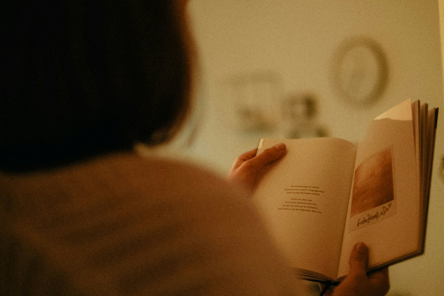 Person reading an open book in their hands indoors.