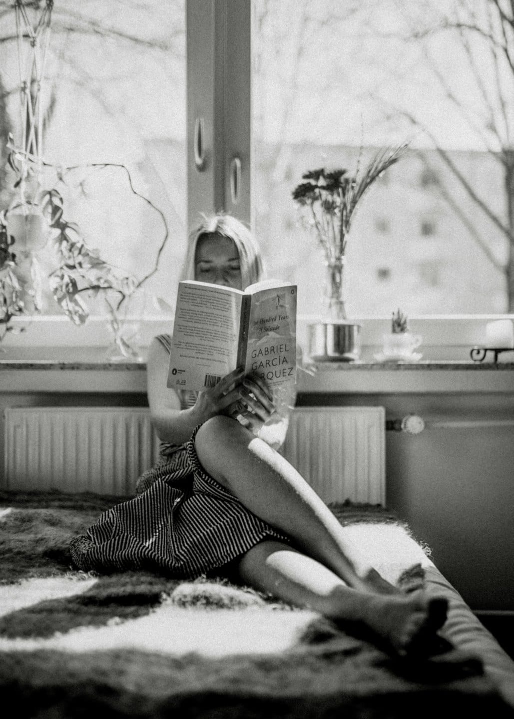 Woman reading a book by a sunny window.
