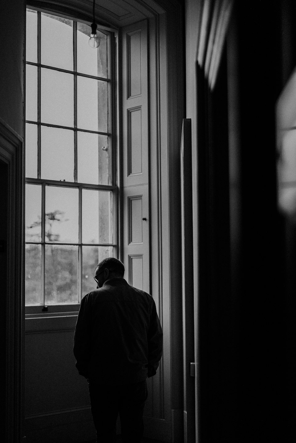 A person stands looking through a large window.
